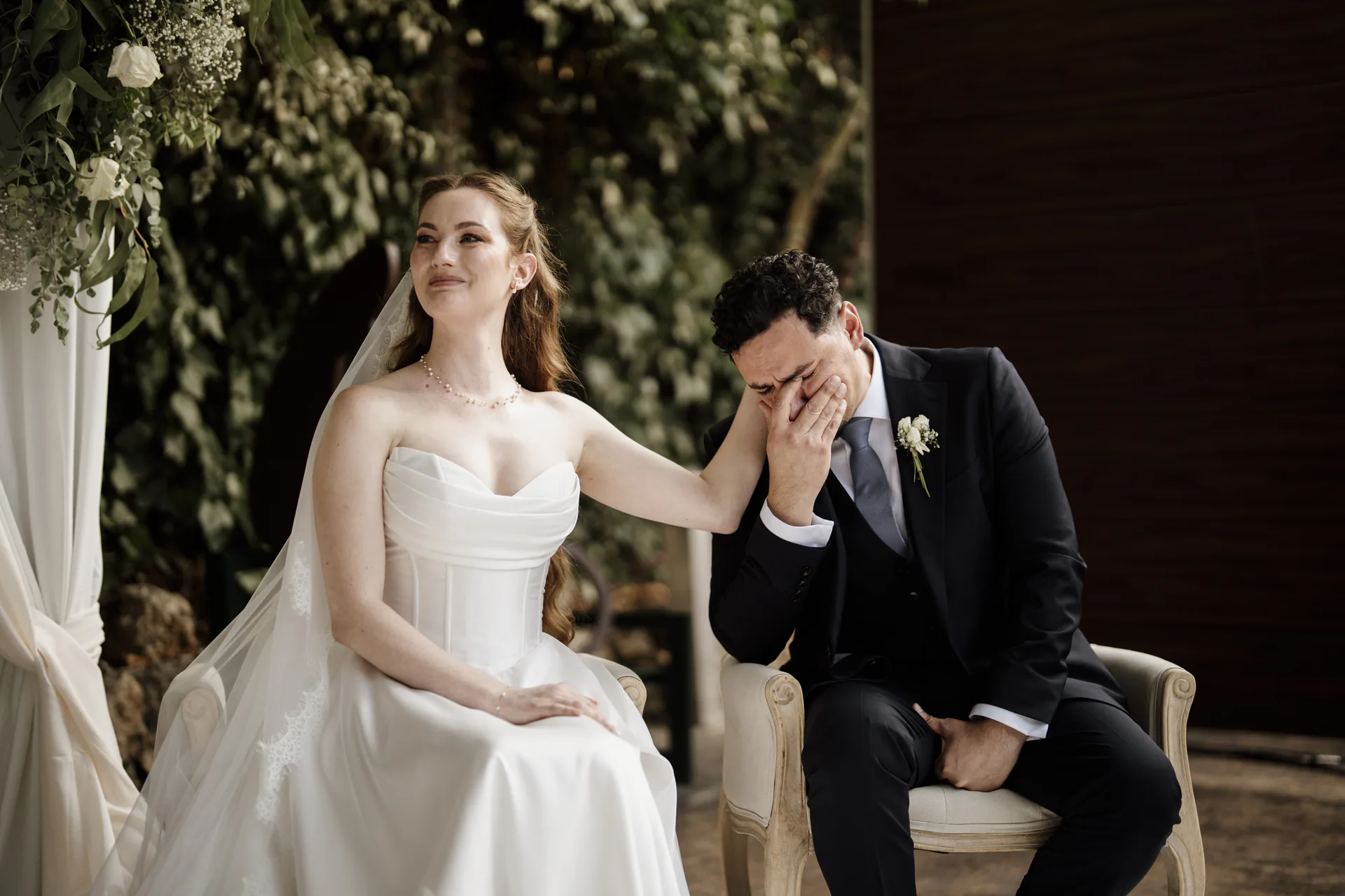 La novia sonríe emocionada y acaricia la cara del novio, que se tapa los ojos llorando durante la ceremonia