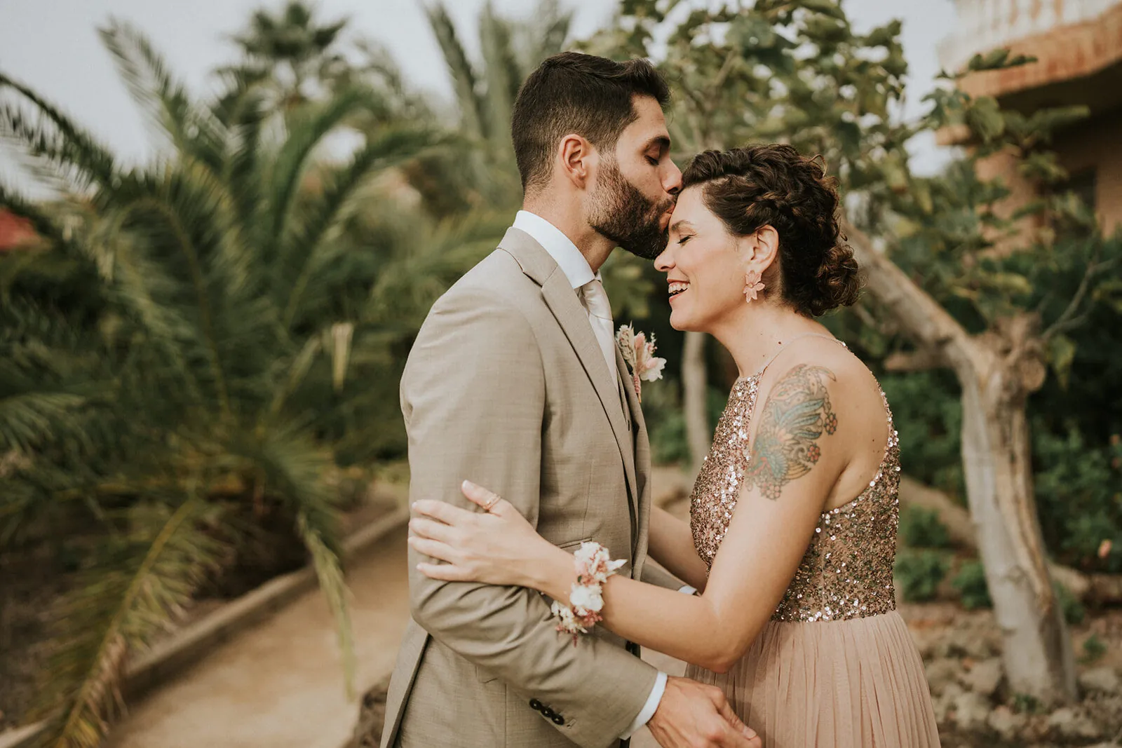 Los novios frente con frente entre palmeras al atardecer